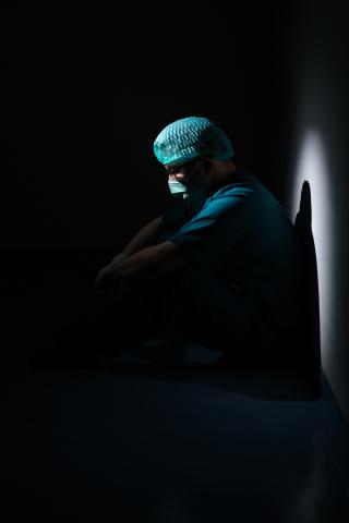 Man in green shirt and blue knit cap sitting on floor