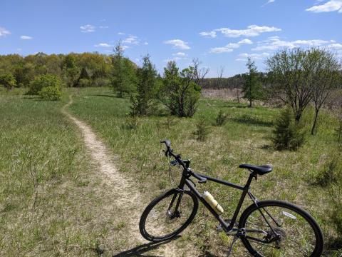 A gray bike on a singletrack path in a field