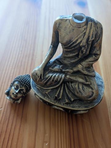 buddha statue with a broken head on a wooden surface