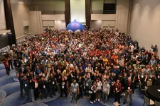 Group photo from DrupalCon Atlanta 2025 with lots of people and an inflatable blue Druplicon