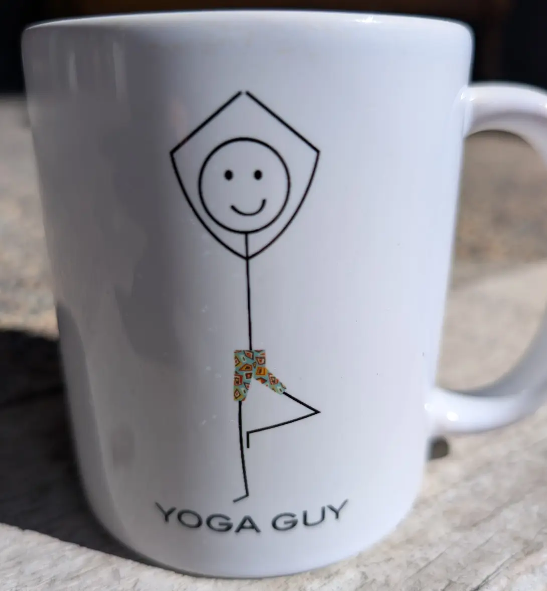 white coffee mug with the stick figure in tree pose and the words yoga guy below